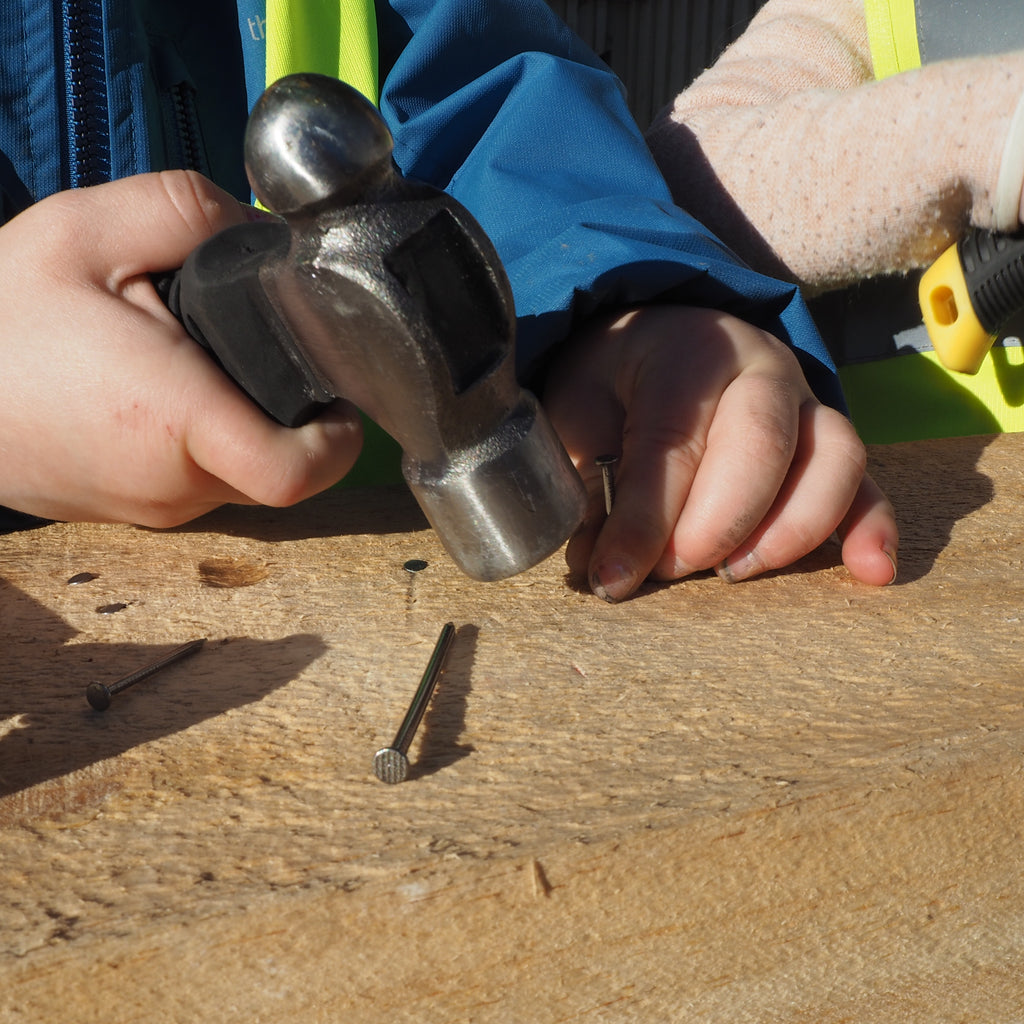 childs hand with nail and ball pein hammer